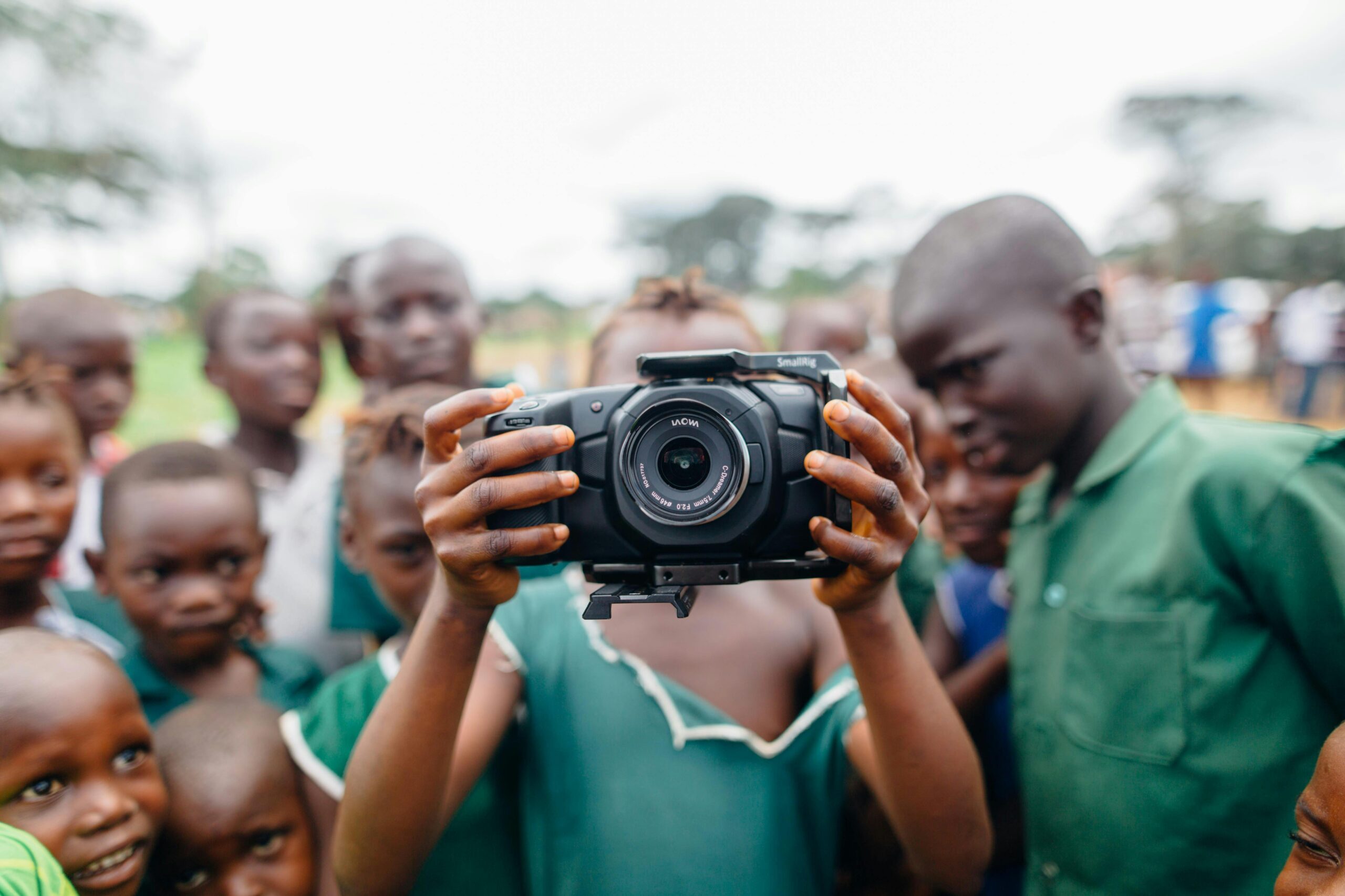 Group of children curiously using a camera outdoors, capturing moments of joy.