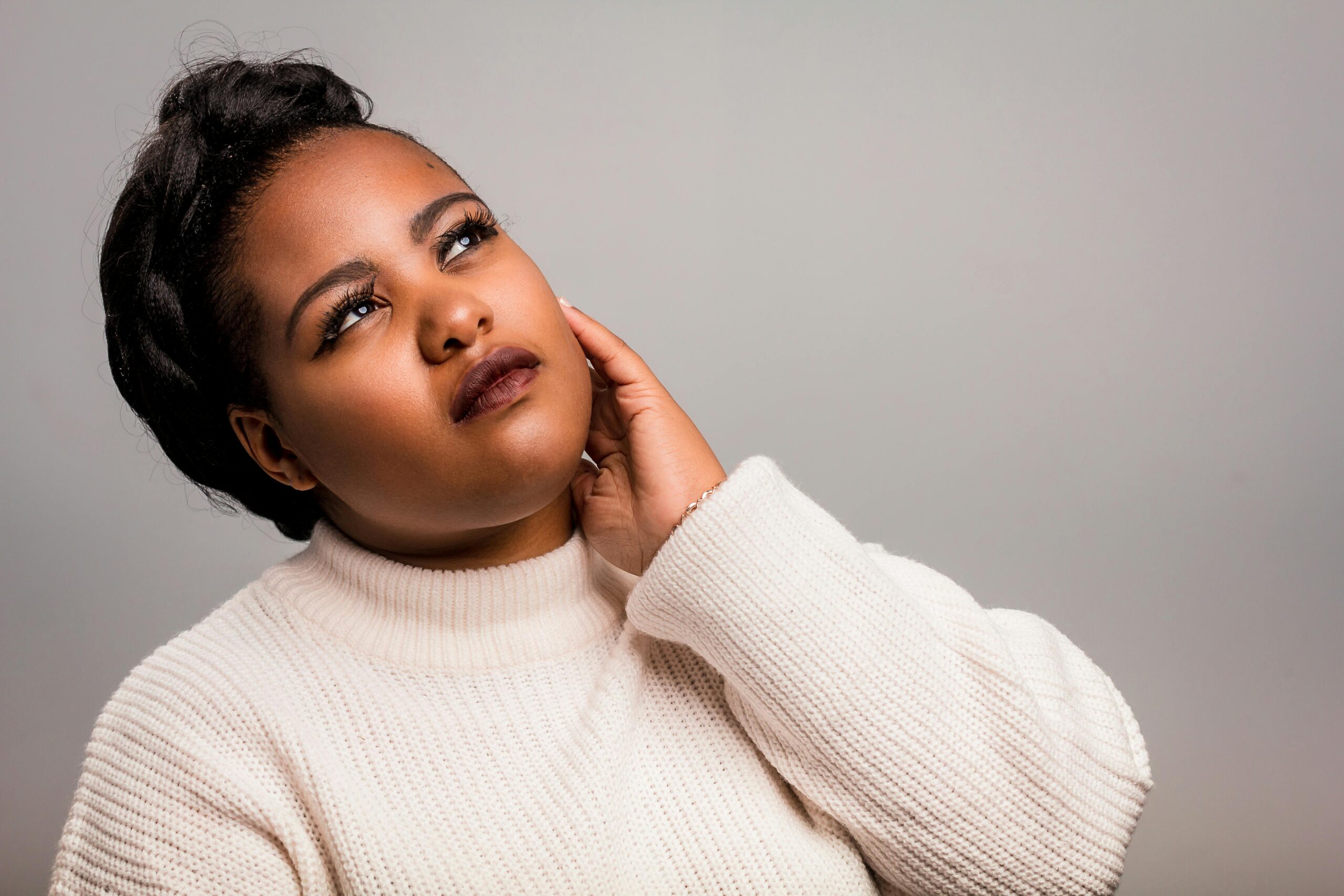 Stylish portrait of a woman in a white sweater looking thoughtful. Ideal for fashion or lifestyle themes.